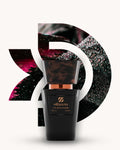 Chogan 054 Extrait de Parfum, schwarzer Parfumflakon mit kupferfarbenem Akzent und dunkler marmorierter Kappe, mittig vor dunklem D-förmigem Hintergrund mit roséfarbenen und smaragdgrünen Reflexen und feinen Wassertropfen, Duftfamilie ähnlich Black Orchid.
